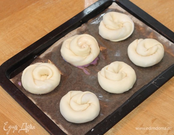 На противень кладем бумагу для выпечки и смазываем ее маслом. Укладываем заготовки булочек на небольшом расстоянии друг от друга. Накрываем противень прозрачным пакетом так, чтобы было место для подъема булочек вверх. Оставляем заготовки в теплом месте минут на 20 или до увеличения булочек в 2 раза.