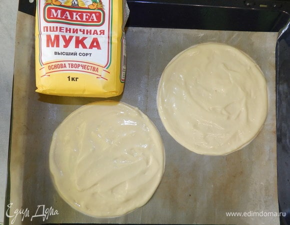 На силиконизированной бумаге для выпечки рисуем 2 круга диаметром 17 см (+/- 1 см). Выкладываем 1,5–2 столовые ложки теста на круг и размазываем его. Выпекаем коржи в разогретой до 170°C духовке 5–7 минут.