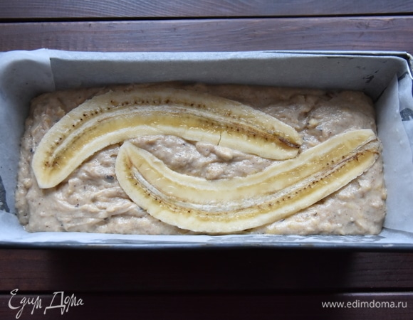 Форму для выпечки смазать растительным маслом. Можно предварительно выстелить ее бумагой для выпечки. Переложить тесто. Постучать формой о рабочую поверхность, чтобы тесто равномерно распределилось. Сверху уложить обе половинки подготовленного банана. Выпекать кекс в духовке, разогретой до 180°C, около 1 часа. Готовность проверить лучинкой.