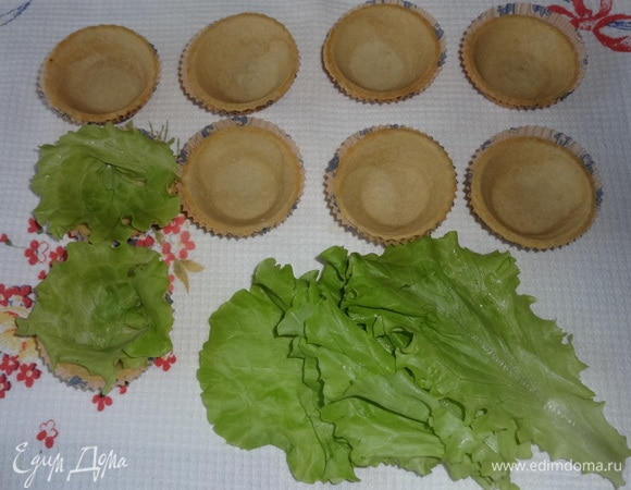 Подготовить тарталетки. Для этого листья салата вымыть, обсушить. Разделить каждый лист вдоль жилки пополам и выложить по кругу в тарталетку. Наполнить корзиночки салатом. Сверху украсить отложенными фасолью, зеленым луком и томатами.