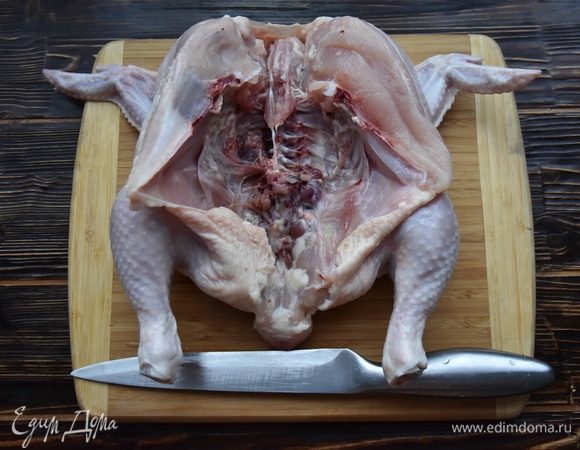 Цыпленка разрезать вдоль по грудке и раскрыть тушку.