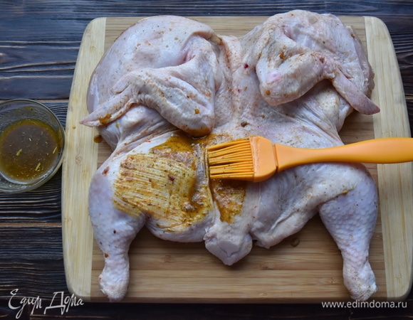 Смазать смесью масла и специй цыпленка с помощью кулинарной кисти.