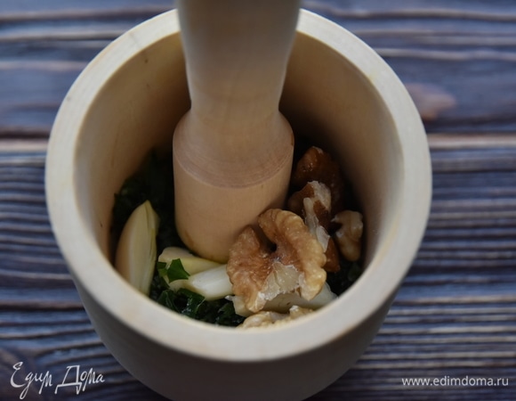 Для заправки в ступке растереть чеснок, зелень и грецкие орехи. Добавить немного соли и чуть воды.