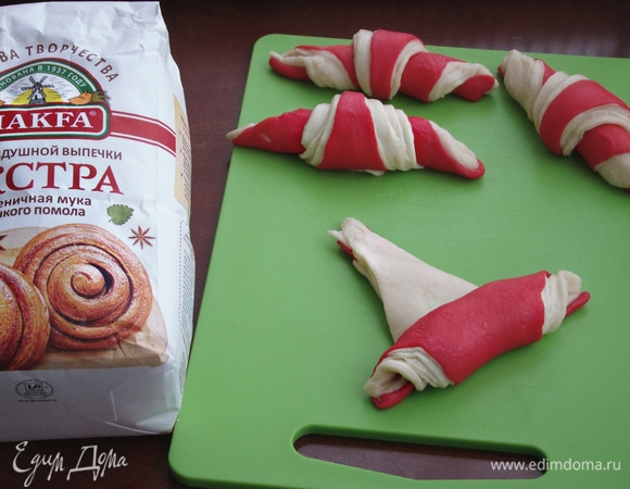 Готовые рулетики уложить на противень, накрыть пленкой или салфеткой и оставить для расстойки минут на 10–15. Затем смазать желтком и поставить в разогретую до 170°C духовку примерно на 20–25 минут.