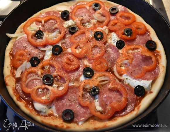 На томатный соус распределяю кусочки моцареллы. Под воздействием жара моцарелла начинает плавиться. Затем раскладываю колбаску, лук, болгарский перец, горсть оливок, нарезанных колечками, и смесь итальянских трав. Короче, все то, что есть в моем холодильнике)