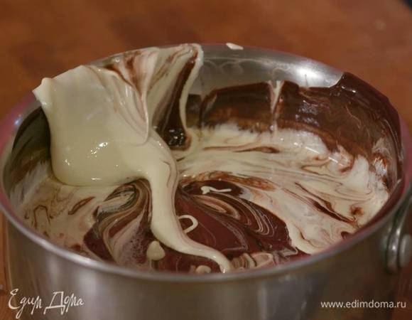 Растопленный шоколад с маслом снять с огня и, помешивая лопаткой, слегка остудить, затем, продолжая помешивать, ввести желтково-сахарную массу.