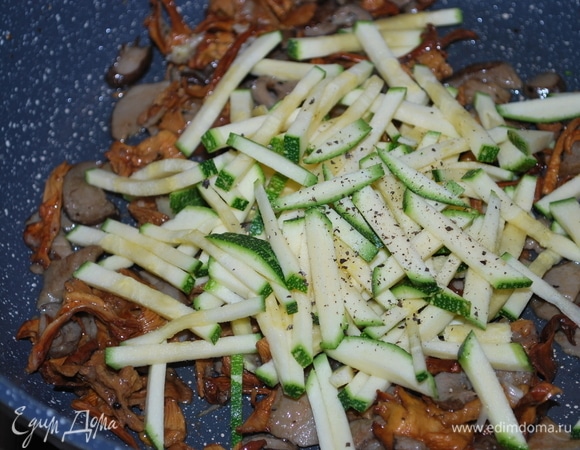 К готовым грибам добавим свежий цукини, нарезанный соломкой, мелкорубленый зубчик чеснока, перец черный по вкусу. Все хорошо перемешаем и обжарим пару минут. В самом конце добавим свежий базилик.
