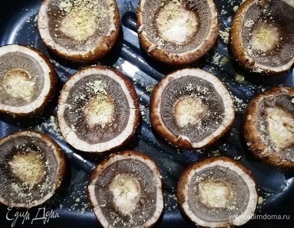Шляпки шампиньонов выкладываем на посыпанный солью и перцем противень. Сверху их также соли и перчим.