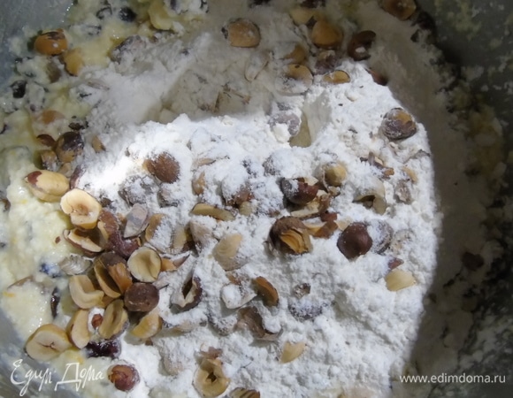 Добавьте половину муки и орехи. Перемешайте.