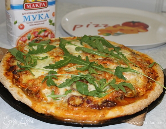 Готовую пиццу нарежьте, переложите на блюдо, добавьте свежую руколу.