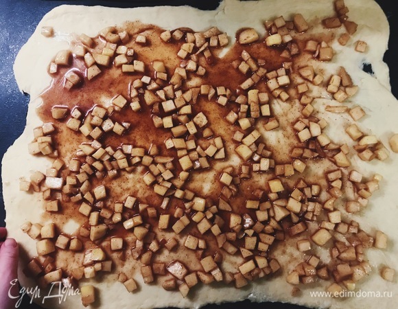 Раскатываем тесто толщиной 1 см. Выкладываем равномерно яблоки и закручиваем в рулет, прижимая концы.