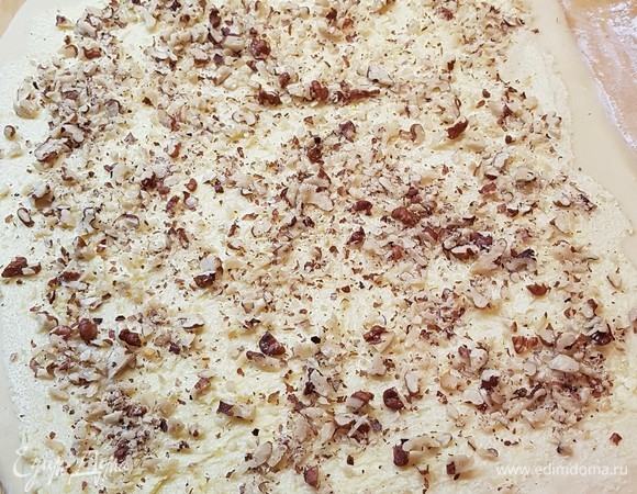 Тесто достать из холодильника. Ему не надо давать время согреться до комнатной температуры. С ним можно начинать работать сразу после того, как достали из холодильника. Тесто раскатать в пласт, смазать лимонным маслом и посыпать орехами.