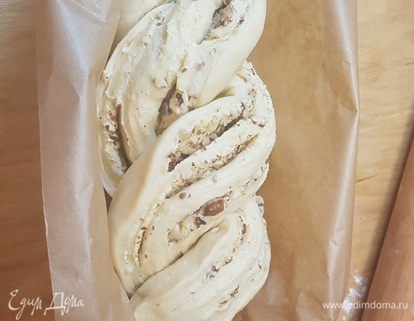 Форму для выпечки застелить пергаментом. Тесто свернуть в рулет. Разрезать его вдоль, не доходя с одного края 1 см. И переплести две половинки между собой. Положить кранц в форму для выпечки и оставить на 2 часа.