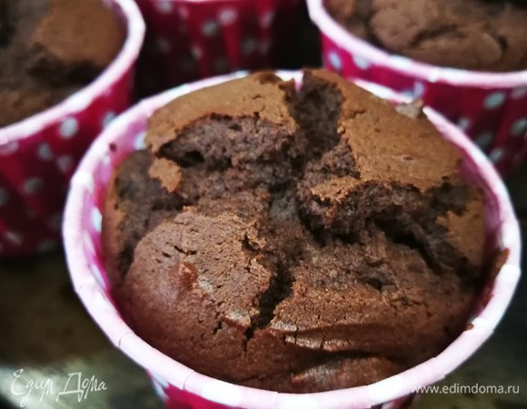 Тем временем все сухие ингредиенты (мучную смесь, какао, ванильный сахар, разрыхлитель) просеять в отдельной миске вместе. Соединить жидкую смесь с сухой, тщательно перемешать. Выложить тесто в формочки на 2/3 и выпекать при 180°C в течение 25 минут.