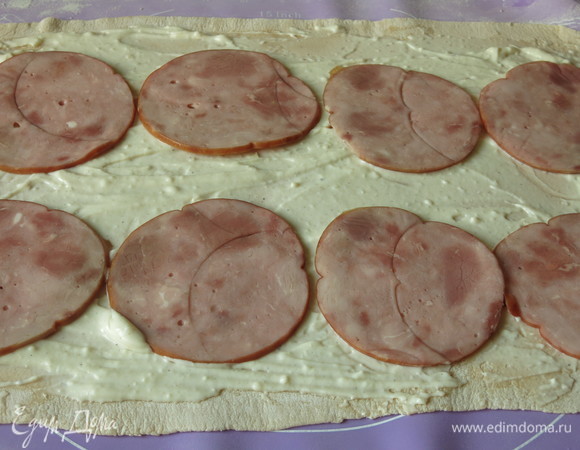 Выкладываем на тесто половину соуса бешамель и ветчину.