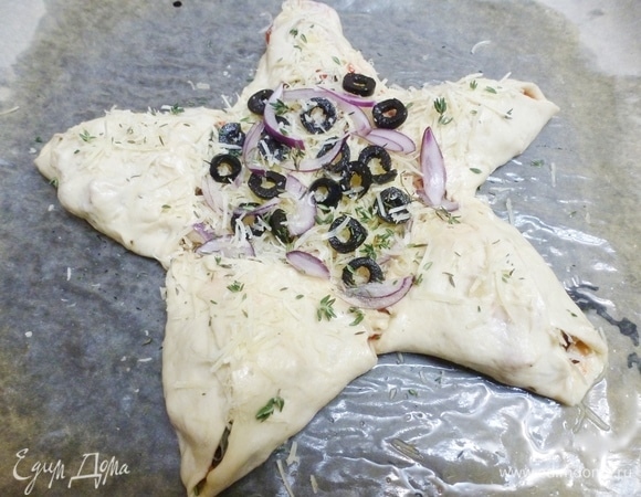 Посыпать сыром, листиками тимьяна и закрыть начинку уголком из теста. Середину посыпать колечками маслин и остатками лука. Посыпать листиками тимьяна. Сбрызнуть маслом.