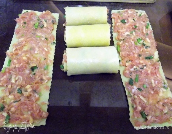 Нанести фарш на листы и свернуть в рулетики.