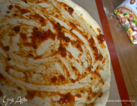 Раскатать тесто, предназначенное для нижней части пиццы. Придать форму (круг или овал). Сформировать небольшие бортики. Смазать слегка томатным соусом. Раскатывать удобнее на форме (или коврике, пергаменте), на которой кальцоне будет выпекаться.