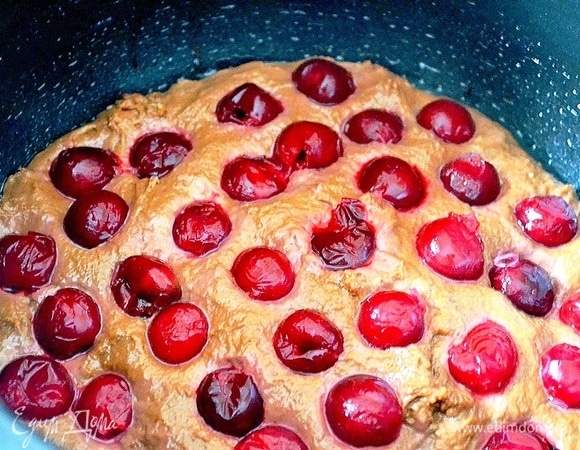 Кладем тесто в противень. Сверху укладываем вишню и вдавливаем ее в тесто.