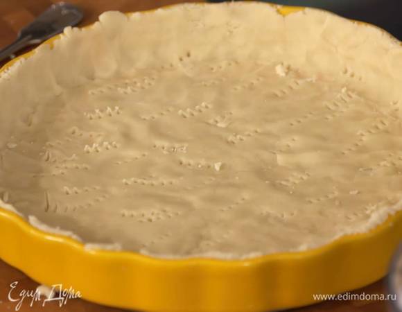 Тесто выложить в форму и равномерно распределить, так чтобы получились бортики, затем часто наколоть тесто вилкой, накрыть бумагой для выпечки, сверху насыпать горох или фасоль.