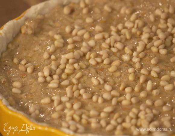 С подпеченного коржа удалить бумагу с бобовыми, выложить начинку и посыпать оставшимися орехами.