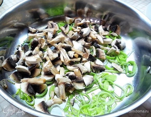 Добавляем нарезанные шампиньоны, перемешиваем и жарим 5–7 минут.
