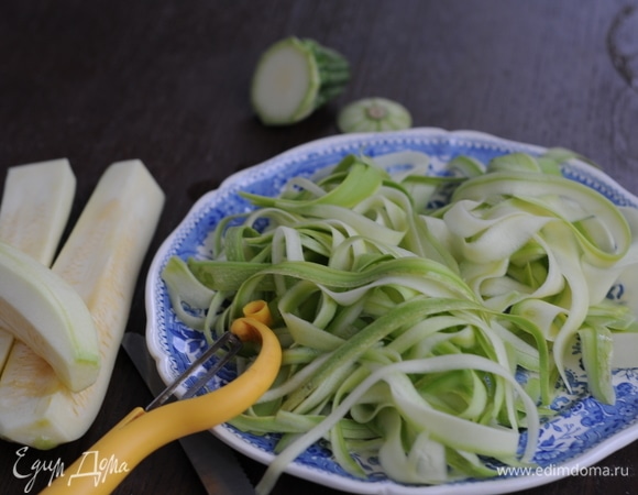 Теперь займемся цукини. Хорошо промыть кабачок и при помощи слайсера, терки или овощечистки нарезать тонкие полоски (как спагетти).