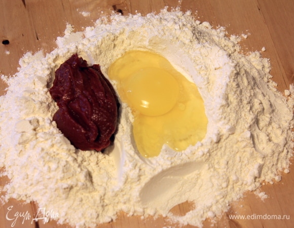 Начнем с красной пасты. Смешиваем оба вида муки, разбиваем туда яйцо и добавляем томатную пасту. Замешиваем тесто сначала вилочкой, потом — руками.