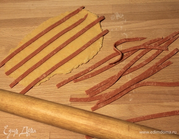 Красный пласт разрезаем на полоски шириной около 4–5 мм и накладываем их на оранжевое тесто.