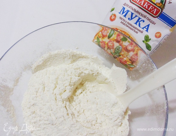 Добавить в муку соль, сахарный песок и сухие дрожжи (1 ч. л.). Перемешивая, постепенно добавить теплую воду, а затем — оливковое масло.