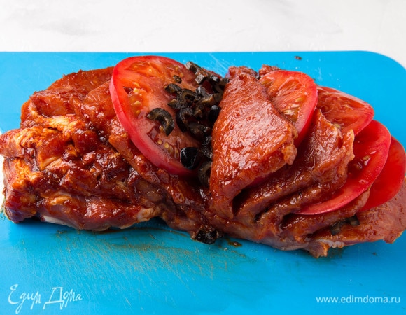 Между кусками мяса положить ломтики помидора и маслины.