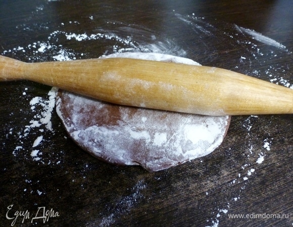 Раскатать тесто в плоский пласт на посыпанном мукой столе.
