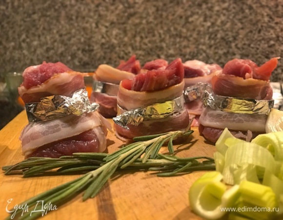 Вырезку режем в виде бочонков, оборачиваем ломтиками бекона и закрепляем фольгой.