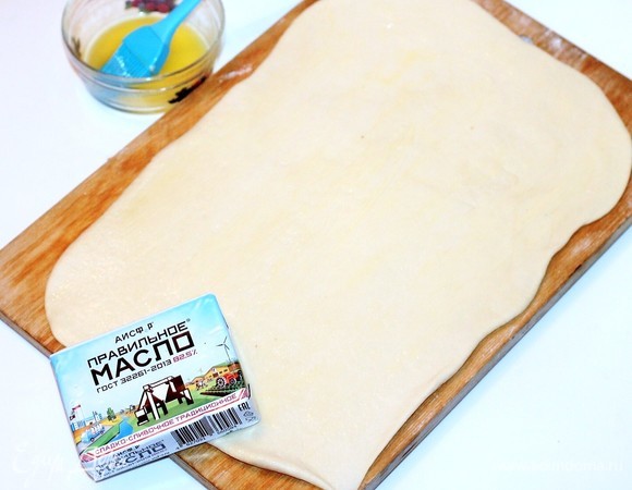 Из этого количества теста выходит 2 больших пирога. Формочки для пирогов диаметром 26 см. Делим тесто на 2 части. С одной частью работаем, другую держим в пакете в холодильнике. Раскатываем тесто в пласт размером 36х27 см без напыления мукой. Смазываем 1/2 часть пласта растопленным сливочным маслом (50 г).