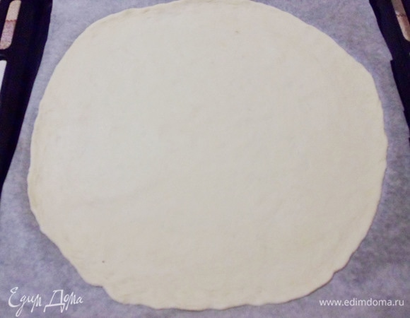 Тесто получается очень мягкое, эластичное, легко раскатывается и хорошо сохраняет форму. Из теста раскатать лепешку диаметром 30–33 см. Основа для пиццы готова. Перенести заготовку на противень. Наколоть тесто вилкой и отправить на 5 минут в разогретую до 220°C духовку.
