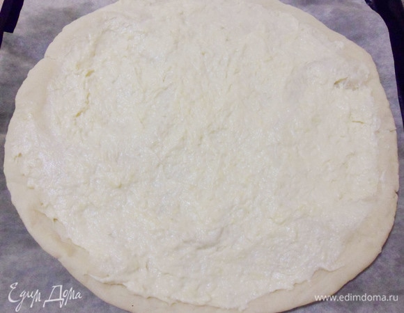 Затем достать лепешку из духовки и на горячую основу выложить сырный соус, отступая от края 1,5 см.