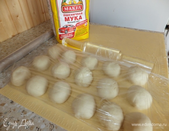 Достаем тесто из чашки. Делим его на 16 частей. Скатываем каждую часть в шарик и даем отдохнуть 20 минут под пищевой пленкой.