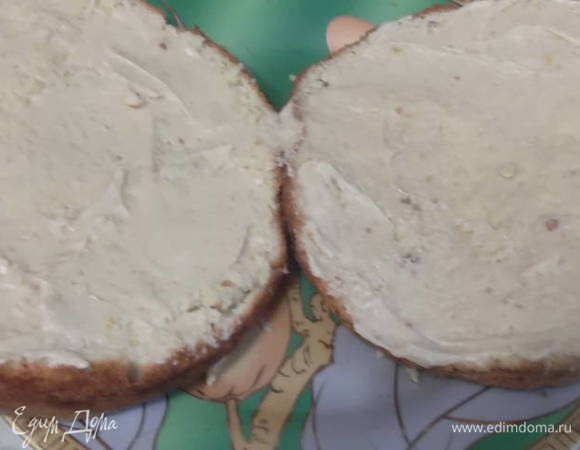 Достать бисквит из формы, накрыть салфеткой и дать остыть в течение 1 часа. Разрезать пополам и каждую половину смазать кремом.