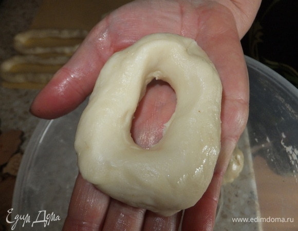 В каждом шарике из теста проделываем в середине отверстие и растягиваем в виде бублика. Смазываем растительным маслом и оставляем под пищевой пленкой еще на 20 минут.
