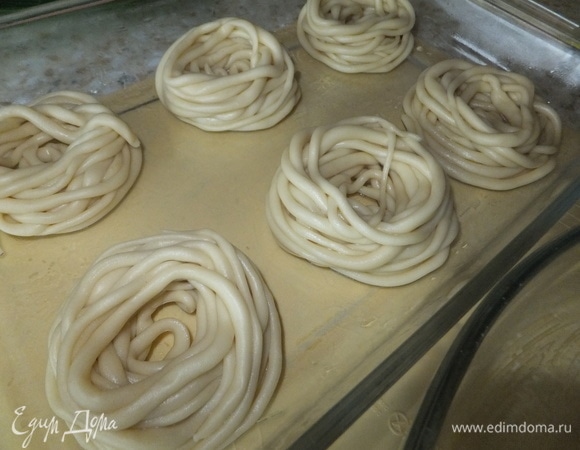 Смазываем форму сливочным маслом, кладем домашние спагетти в форму, сворачивая их в гнезда. Сюда же добавляем кусочки сливочного масла и 150 мл воды.