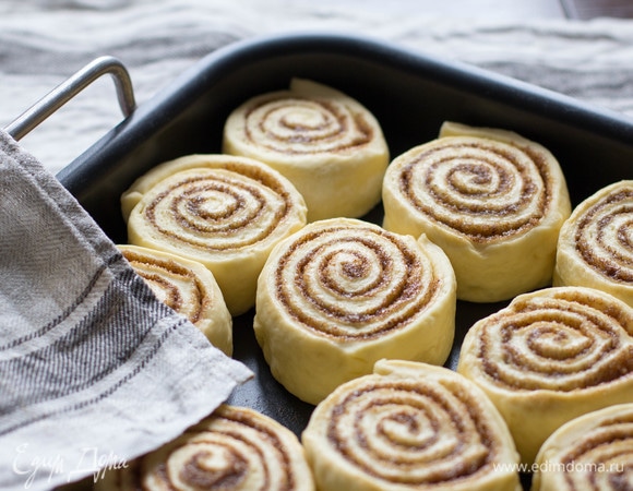 Рулет нарезать на ломтики по 4–5 см. Выложить синнабоны на противень, застелить бумагой для выпечки. Или поставить в форму для выпечки.