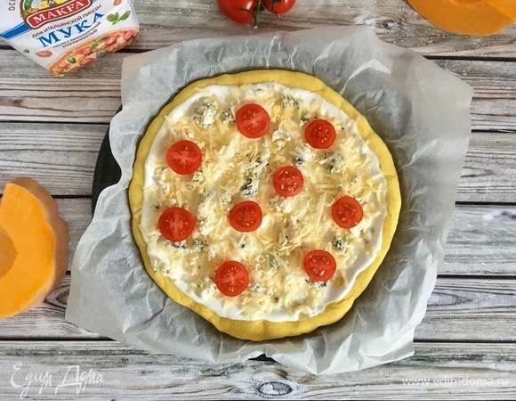 Сверху посыпать сыром и разложить помидоры. Выпекать при 200°C 15–20 минут. Готовую пиццу по желанию можно украсить свежей зеленью.