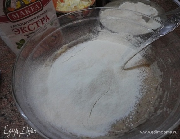 В опару с пряностями добавляем муку частями, перемешивая ложкой. Оставшуюся муку высыпаем на стол, выкладываем на нее тесто.