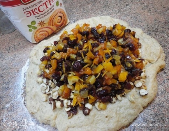 На посыпанный мукой стол выкладываем тесто, разравниваем руками, сверху выкладываем орехи и сухофрукты, впитавшие в себя сок и алкоголь.