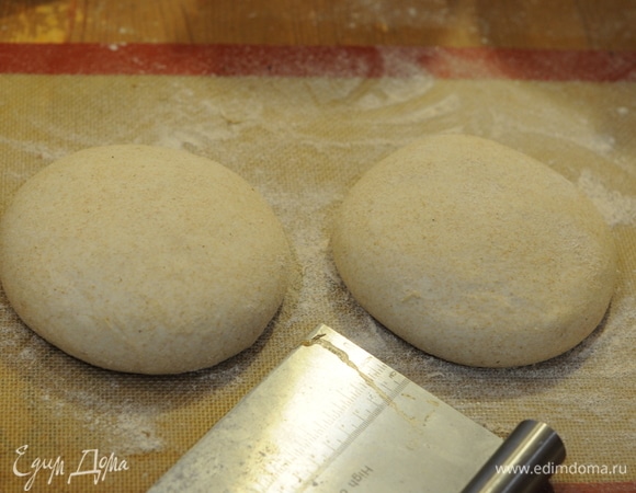 Тесто подошло. Аккуратно кладем на посыпанный мукой стол. Делим на 2 части, закругляем и оставляем, накрыв миской на 15 минут, чтобы тесто отдохнуло.