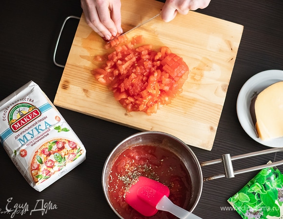 Начинка: самое главное — смазать раскатанное в тончащий пласт теста томатом (соусом) из помидоров и очень обильно. Никакой томатной пасты, никакого кетчупа — ни в коем случае. Для приготовления томата нам потребуется 250 г консервированных в собственном соку помидоров, с которых нужно снять кожицу и размять вилкой. Томаты вместе с соком вылить в сотейник. Туда же нарезать мелким кубиком 180 г свежих бланшированных помидоров. Сотейник поставить на средний огонь и довести до кипения. Туда положить две чайные ложки сахара (помидоры его очень любят). Попробуйте, если нужно, досолите. Также добавьте 0,5 ч. л. сушеного орегано и черного перца и еще немного поварите.