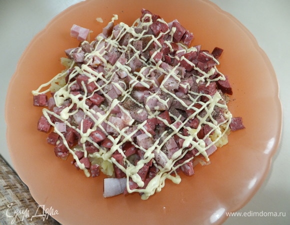 Нарезаем грудинку и колбасу мелким кубиком. Делаем сеточку из майонеза.