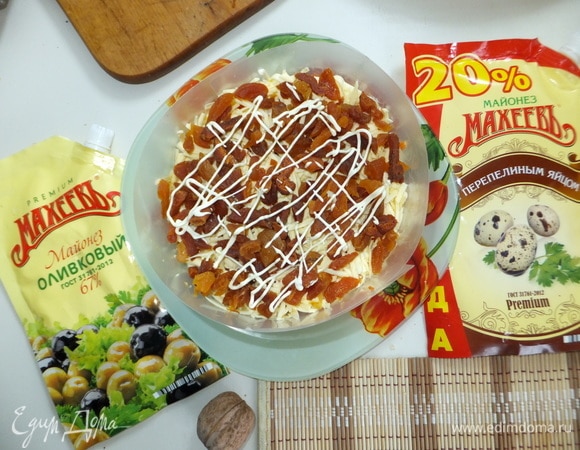 Курагу кладем в кипяток и накрываем крышкой на 5 минут. Натираем сыр на терке. Затем обсушиваем бумажными полотенцами курагу и нарезаем мелким кубиком. Кладем слой сыра, на сыр — курагу. Делаем майонезную сеточку.