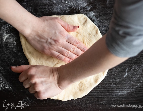 При раскатке теста лучше не использовать скалку, ведь так можно выдавить из теста пузырьки воздуха и сделать его резиновым. Лучше делать это руками, это не так сложно, как кажется сначала. Просто положите шар теста на стол, посыпанный мукой, и тяните его руками в стороны, постепенно доводя его до толщины в 3 мм и придавая лепешке круглую форму. Загните края, формируя бортик шириной около 0,7 мм.