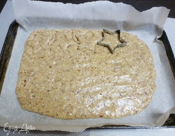 Распределить тесто по бумаге для выпечки и вырезать печенье любой формы. Не стоит делать слишком фигурное, так как готовое печенье такое хрупкое, что мелкие детали могут раскрошиться. Перед выпечкой печенье необходимо охладить в холодильнике 30 минут. Сначала я хотела выдавить печенье и убрать остатки теста (как на фото), но тесто очень рассыпчатое и просто распадается в руках, поэтому я разделила тесто на два шарика, охладила их в холодильнике и только потом выдавливала печенье. С холодным тестом работать значительно лучше, имейте это в виду!